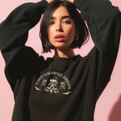 Christmas sweatshirt with "SEASONS SCREAMINGS, DARKLING" text arched over a skull wearing Santa hat. Bats, flowers, and ornate designs surround the skull in vintage-inspired style.
